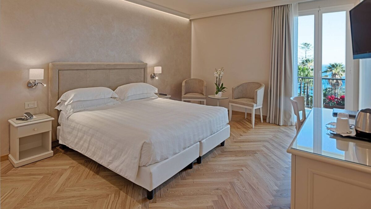 Camera deluxe Hotel Paradiso Sanremo con velette luminose integrate a soffitto e luce monomissione calda, progetto architetto Ennio Scarella.